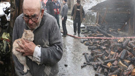 Evinin yanışını kedisine sarılıp izledi